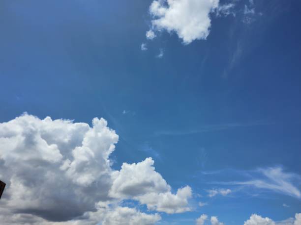 Bright sunlit blue sky in the background, set of beautiful white firmament clouds with the movement of the wind above the city