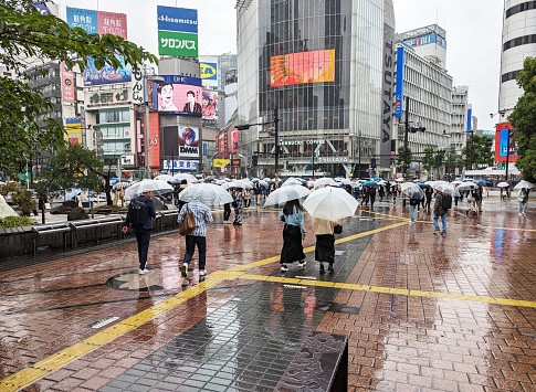 May 23, 2023 - Shibuya, Japan: Pedestrians walk near Shibuya Scramble Crossing outside Shibuya Station on a rainy spring afternoon.