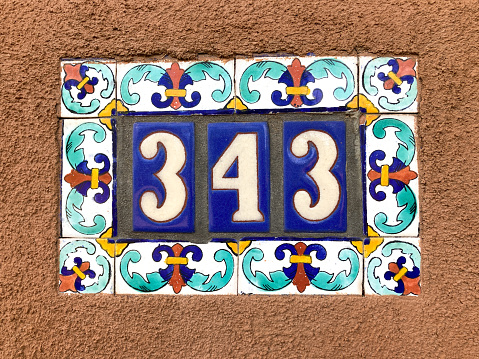Ceramic Number 343 Street Address; Colorful Mexican floral tiles on adobe wall. Shot in Santa Fe, NM.
