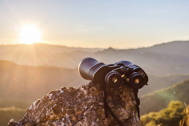 istock binoculars on top of rock mountain at beautiful sunset background. 1498811745