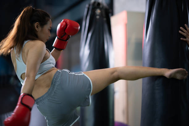 istock Asian woman kicking boxing sand bag. 1498812221