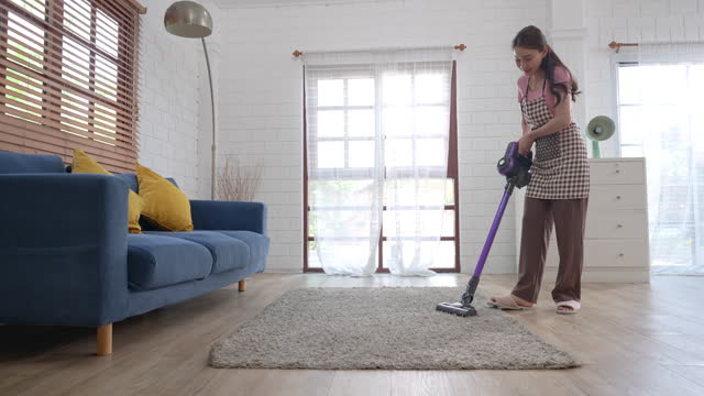 Happy Asian woman spending the weekend cleaning the house.