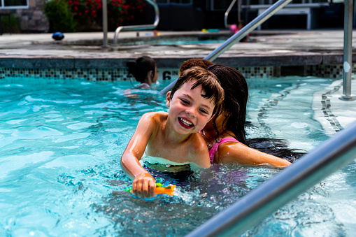 As the sun beats down on a scorching summer day, four multiethnic siblings find solace and delight in the refreshing depths of a pool. Taking the lead is a 14-year-old African American girl, her shoulder-length hair dyed blond, radiating confidence and grace. Alongside her, a multiethnic girl with long, ebony tresses, and a vivacious 7-year-old with her dark hair neatly tied in a playful ponytail, add to the vibrant scene. Completing the ensemble is a mischievous 5-year-old boy, his infectious laughter and boundless energy lighting up the water like sun-drenched diamonds.