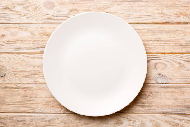 istock Top view of empty light plate on wooden background. Empty space for your design 1498827245