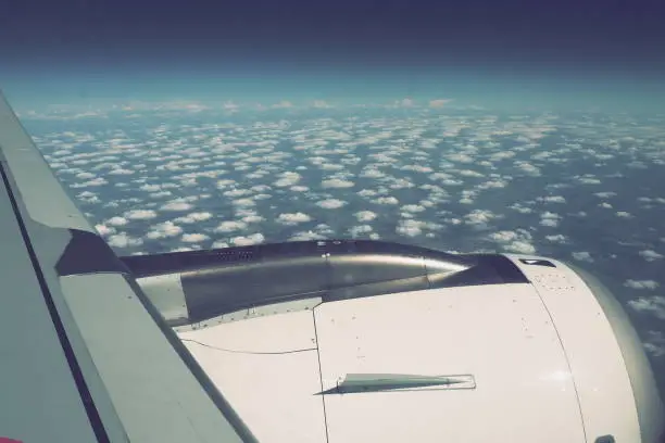 Aircraft engine and wing on the border of atmosphere and space. The edge of the troposphere. Horizon over the Earth. Flights, travel and tourism. View from a window or porthole. Clouds and blue sky