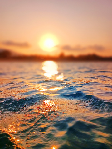 Sea wave splash, sunset blurred bokeh background, ocean water surf ripple texture, sunrise soft focus, tropical island beach dawn, sundown orange sun shine reflection, summer holiday, vacation, travel