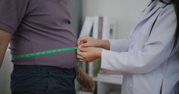 female nutritionist measuring waist of overweight man in weight loss clinic - dieting healthy eating healthy lifestyle tape measure imagens e fotografias de stock