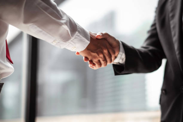 istock Close up of two business people shaking hands while sitting at the working place 1498836921