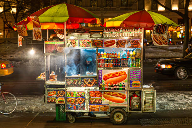 Outdoor food cart on city sidewalk selling hot dogs Colorful food cart on city sidewalk in winter night hot dog stand stock pictures, royalty-free photos & images