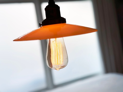 Detail of a rustic wall lamp with Edison lightbulb in a hotel room