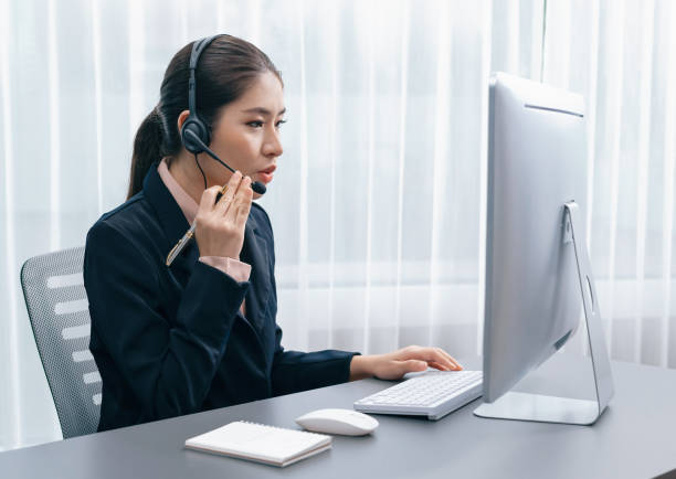 istock Enthusiastic asian call center with headset and microphone working on her laptop 1498844140