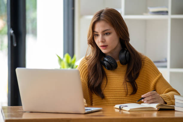 istock Distance Education. E-learning, Study online, Smiling beautiful woman sitting at desk and wearing headphone head set study online class zoom google meet discord, Happy engaged girl attending for learn 1498848404