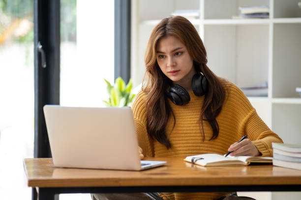 istock Distance Education. E-learning, Study online, Smiling beautiful woman sitting at desk and wearing headphone head set study online class zoom google meet discord, Happy engaged girl attending for learn 1498848443