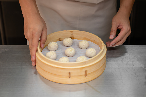 Chef preparing soup dumplings in basket. Uncooked dumplings in basket.