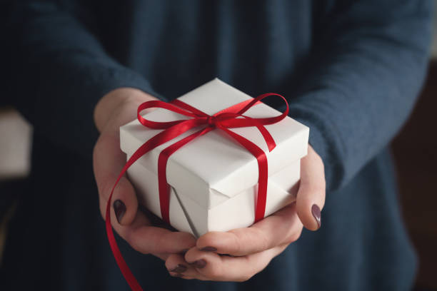 istock young female hands holding gift box with red ribbon 1498857927