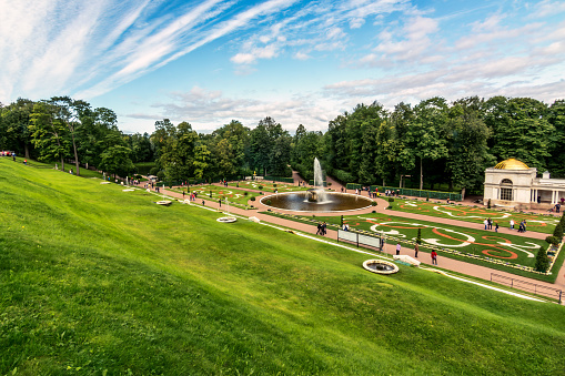 St Petersburg, Russia - August 27, 2017: The view from the Upper Garden at Peterhof offers a captivating sight of the beautifully landscaped Lower Garden, with the enchanting Bowl Fountain as its centerpiece. Surrounded by lush greenery and carefully crafted gardens, this serene oasis showcases the harmonious blend of nature and artistry that defines the splendor of Peterhof.