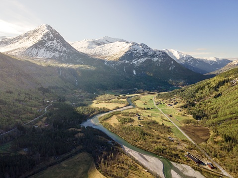 An aerial shot of a river running through a lush valley surrounded by mountains in Norway.