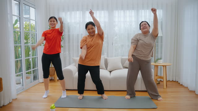 Family consisting of obese and non-obese mother and daughter dancing joyful acrobatics at home, fitness concept, family relationship