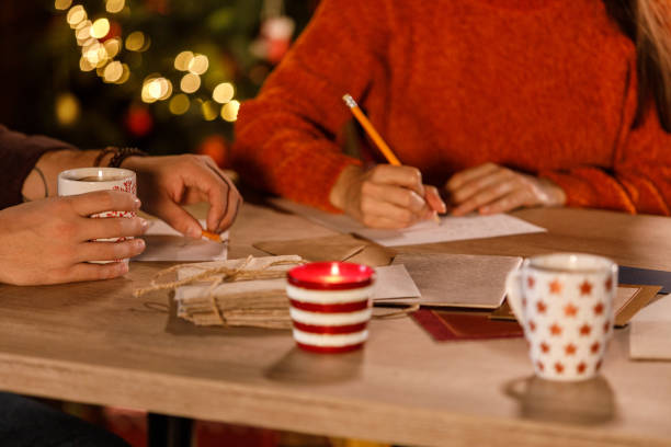 istock Young couple bonding while writing Christmas letters and cards together 1498870850