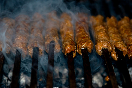 Making Spicy seekh kebabs are being grilled on burning charcoal in barbeque at a dinner party at night