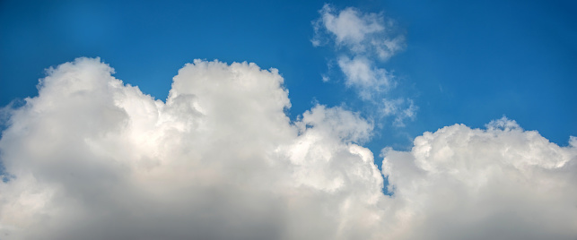 A panoramic view of scattered white clouds against a blue sky