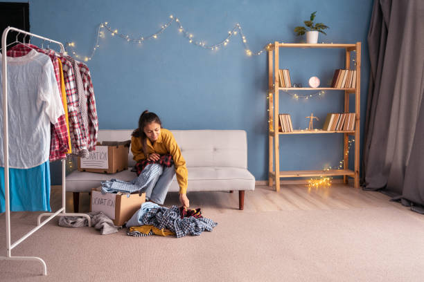 femme triant et emballant des vêtements sur une boîte de don dans sa chambre, concept de don. - volunteer organized group casual charity and relief work photos et images de collection