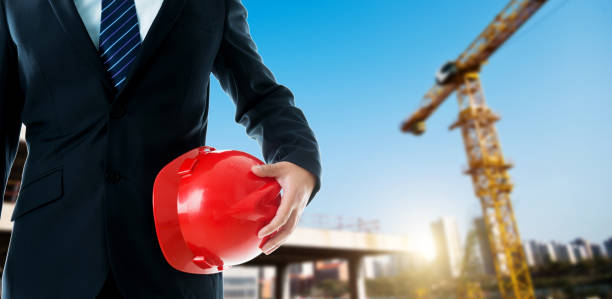 istock Businessman standing and holding a red hardhat 1498876159