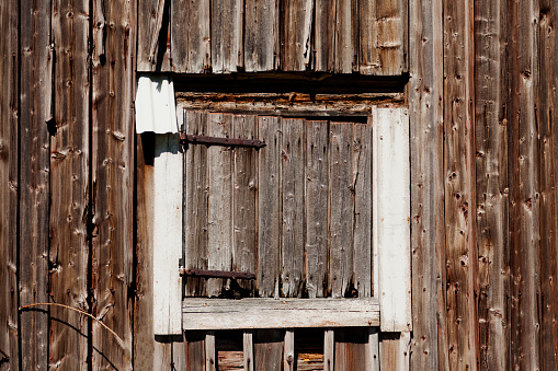 Old wooden cabin framed window looking out into green pasture. Vintage, rustic wood theme.