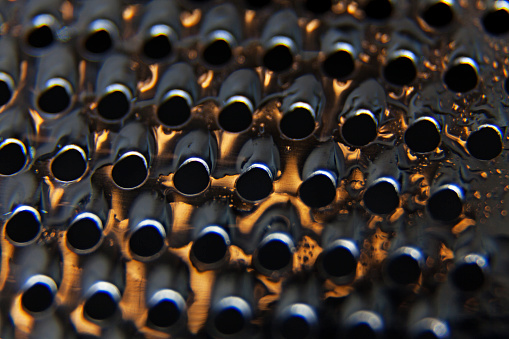 metal grater close up with water drops and extra orange light, macro lens