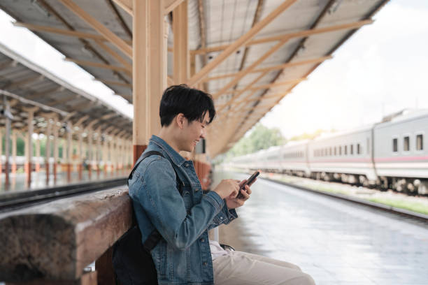 istock Young handsome man sitting and using smartphone at train station 1498877747