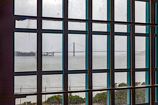 Looking at the Golden Gate Bridge from a window of the maximum security federal prison of Alcatraz, located on an island in the middle of the San Francisco Bay, California, USA. American concept.