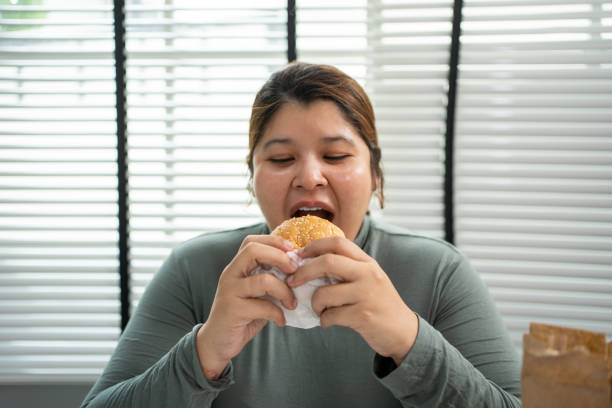 istock Asian woman eating a hamburger at the office. 1498879849