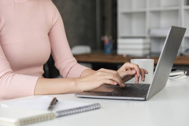 istock Woman sitting at desk and working at computer hands close up 1498879897