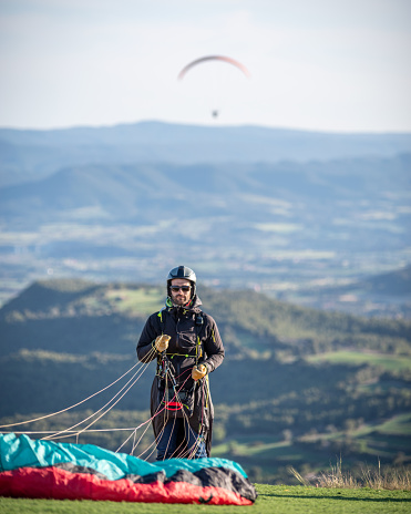 16 may 2023 - Igualada, Spain: Paraglider ready to fly in the mountain with a paraglider flying in the backgroud
