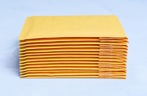 Close-up of yellow padded envelopes stacked on a grey concrete background.