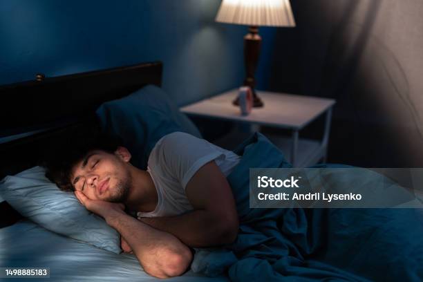 Peaceful Young Man Sleeping In A Comfortable Bed Alone At Home Enjoying His Orthopedic Mattress And Cozy Pillow Good Sleep Concept Stock Photo - Download Image Now