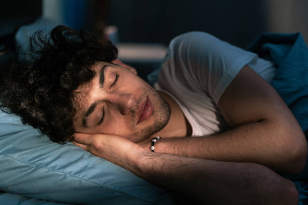 istock Handsome young man sleeping on pillow in dark room at night, resting at night time. Healthy sleep 1498885192