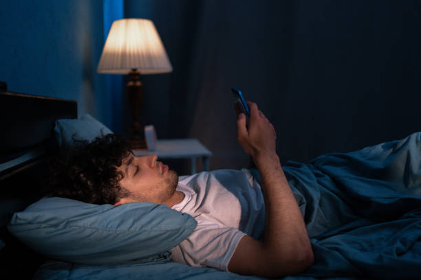 istock Dark night young man looking at mobile phone screen texting late awake in bed insomnia. Serious guy depressed addicted to social media. 1498885209