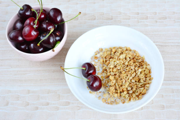 granola with cherries in white bowl, copy space