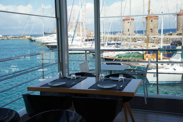 istock Restaurant interior  and  Medieval Windmills in Mandraki Harbour at the background, Island Rhodes, Greece 1498892515