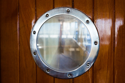 Round porthole on a wooden door inside the ship.
