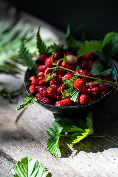 istock Freshly gathered wild strawberries on wooden bench. 1498894310
