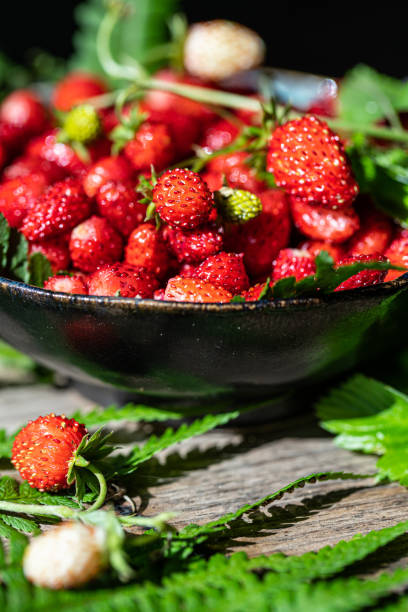istock Freshly gathered wild strawberries on wooden bench. 1498894351