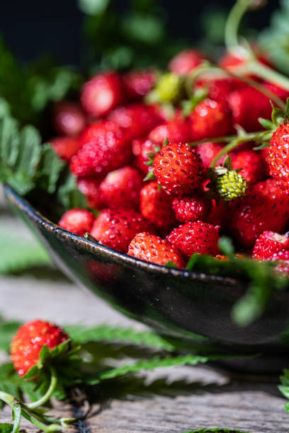 istock Freshly gathered wild strawberries on wooden bench. 1498894354