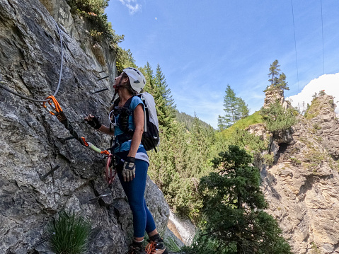 Wide angle view of sporty woman climbing in summer on Via Ferrata in Switzerland
