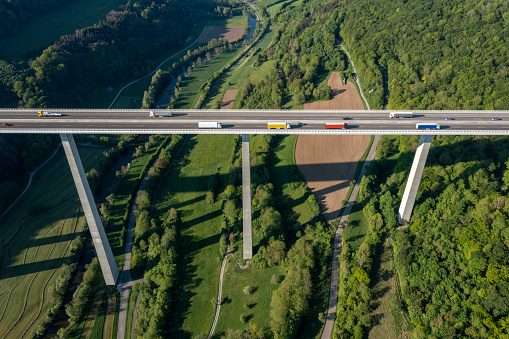 Highway bridge with truck traffic in springtime, aerial view.