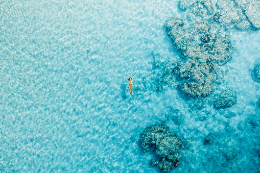 Woman swimming in blue ocean on her vacations. Aerial view, top view
