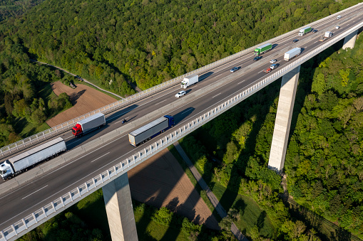 Aerial view of a highway bridge with truck and car traffic in green, spring landscape.