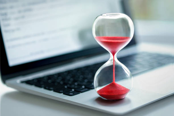 Hourglass on laptop computer A red hourglass on laptop computer - concept for time management urgency stock pictures, royalty-free photos & images