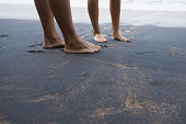 Beach travel - foots of couple in love walking on black sand beach in Sri Lanka.